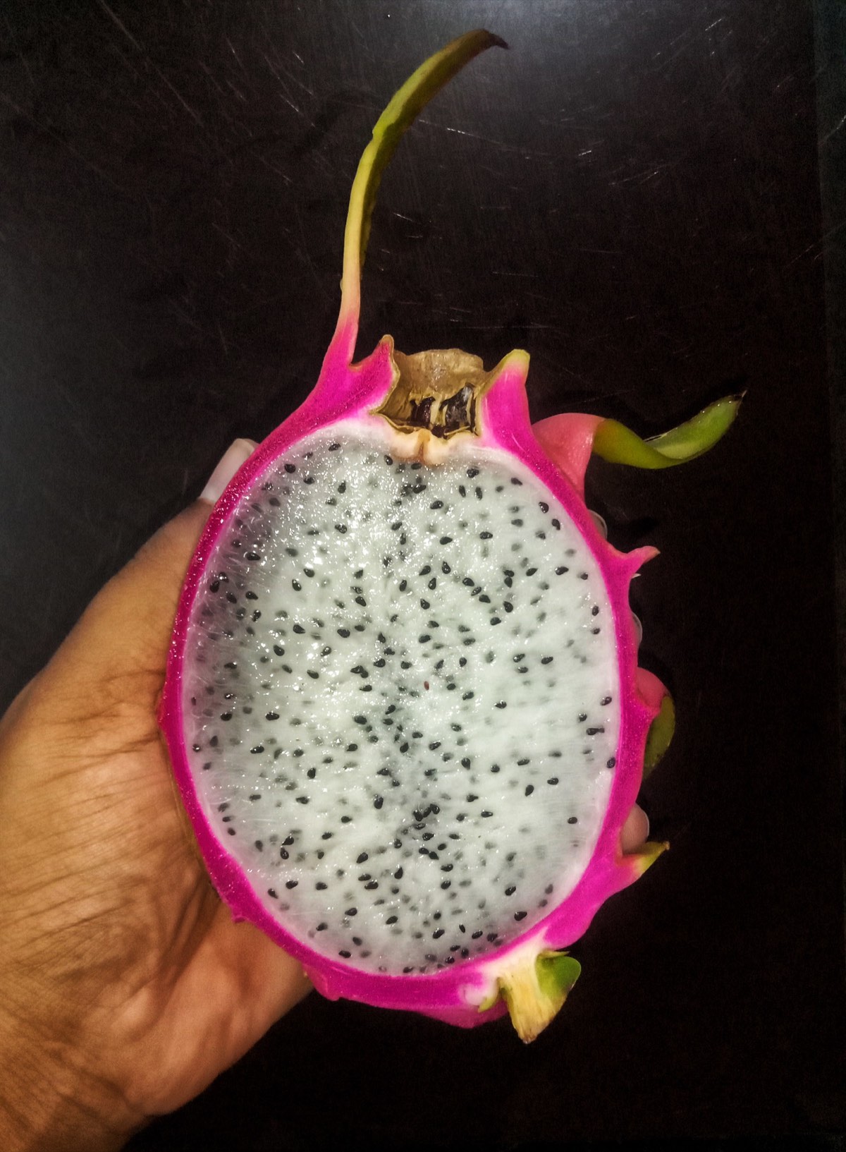 A halved red dragon fruit showing bright magenta flesh