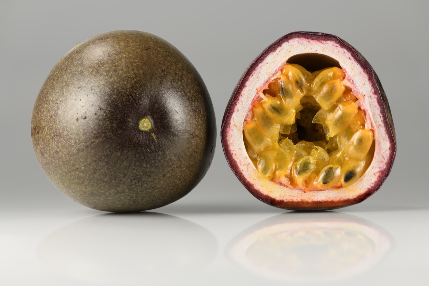 Whole and halved passion fruits showing yellow pulp and seeds